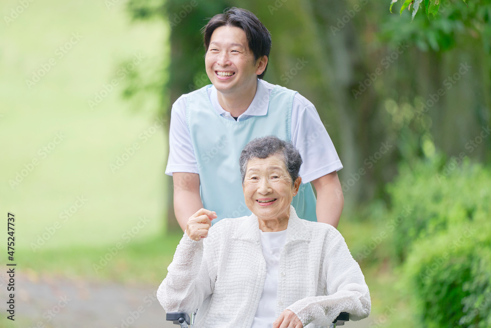 介護士と車椅子に乗る高齢者　屋外