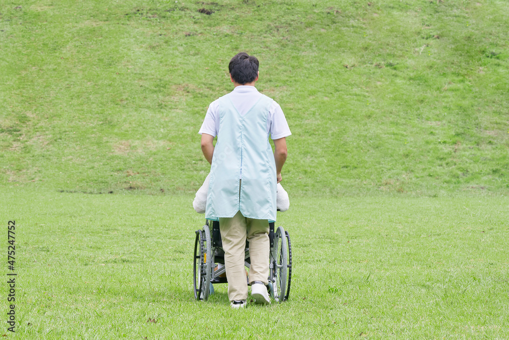 介護士と車椅子に乗る高齢者　屋外