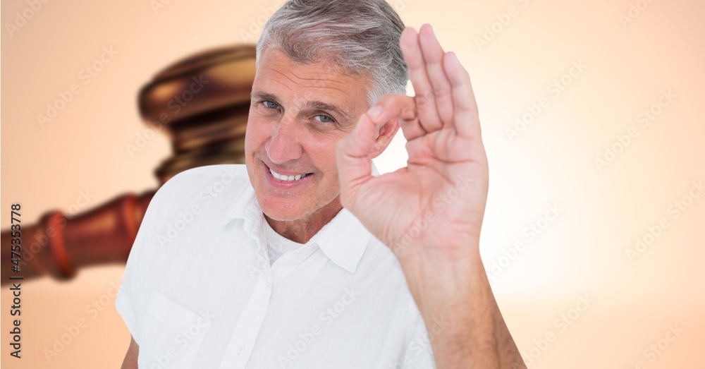 Composite image of caucasian senior man gesturing okay sign with his hand against a gavel