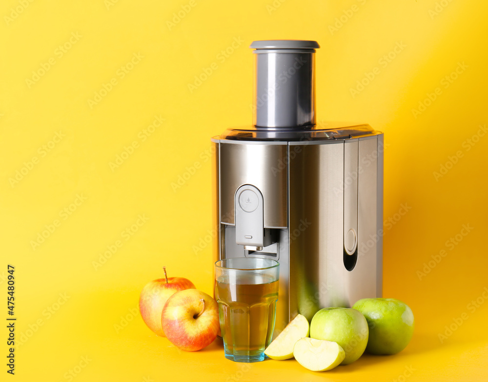 Modern juicer with fresh fruits on color background