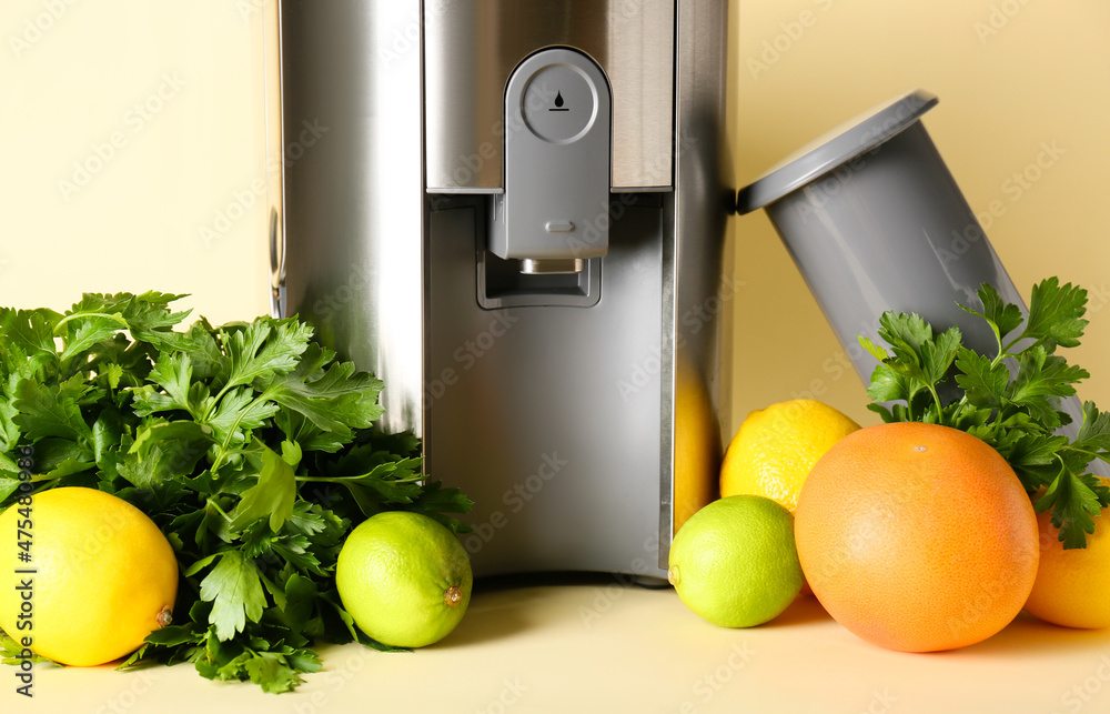 Modern juicer with fresh fruits on color background