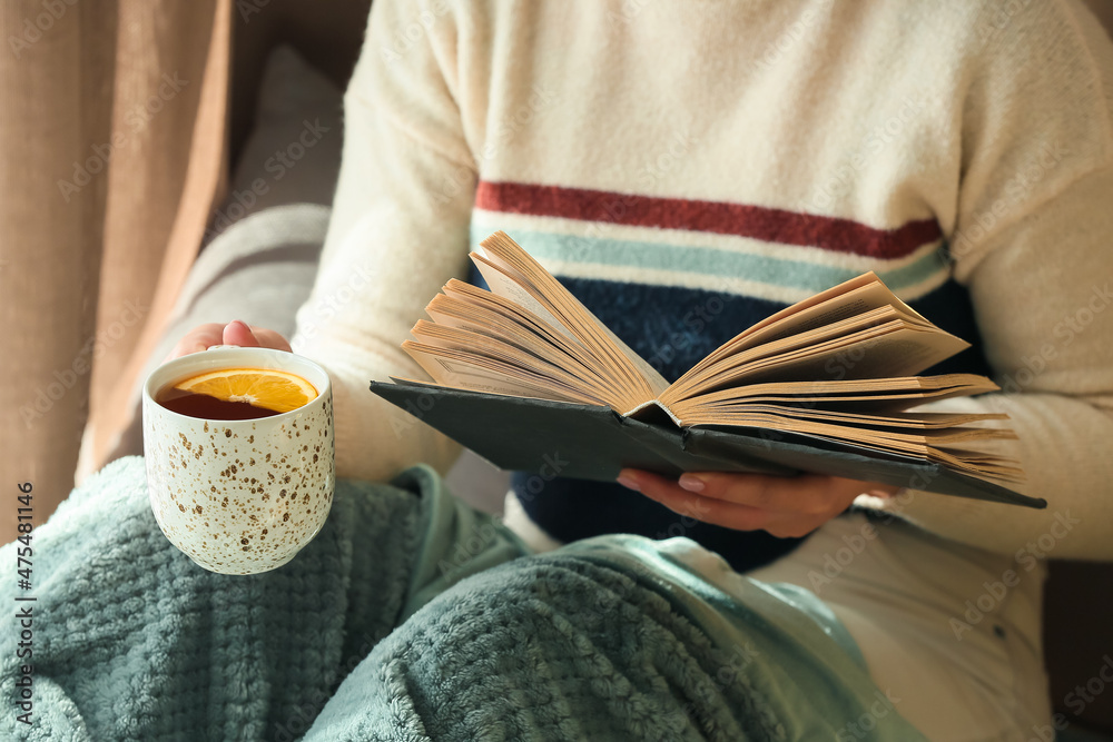 女人在房间里端着一杯茶看书