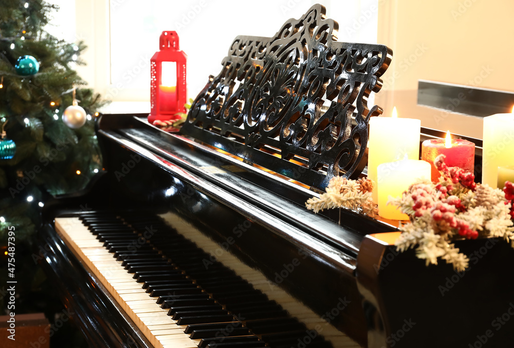 Grand piano with burning candles in room decorated for Christmas