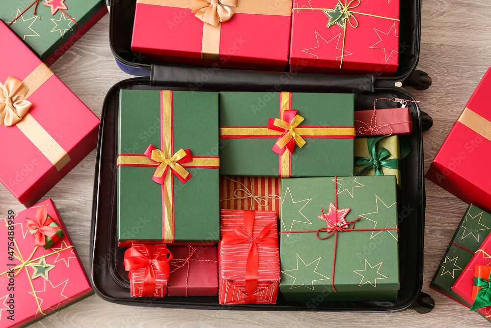 Blue suitcase with Christmas gift boxes on floor