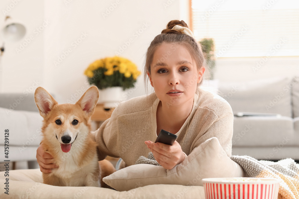 年轻女子带着可爱的柯基犬在家看电视