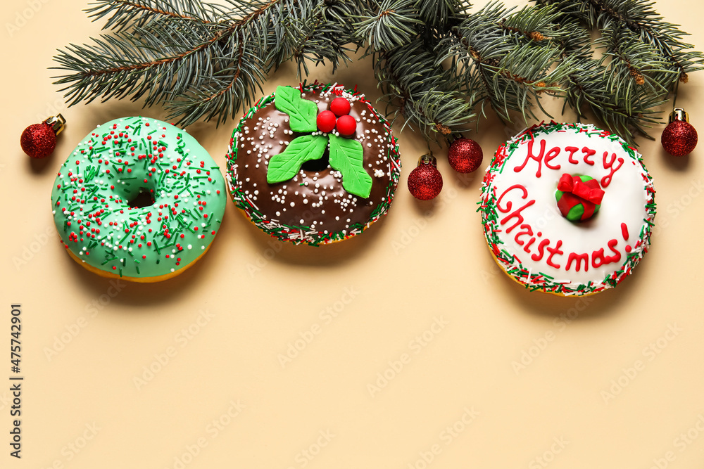 Tasty Christmas donuts with fir tree branches and balls on beige background