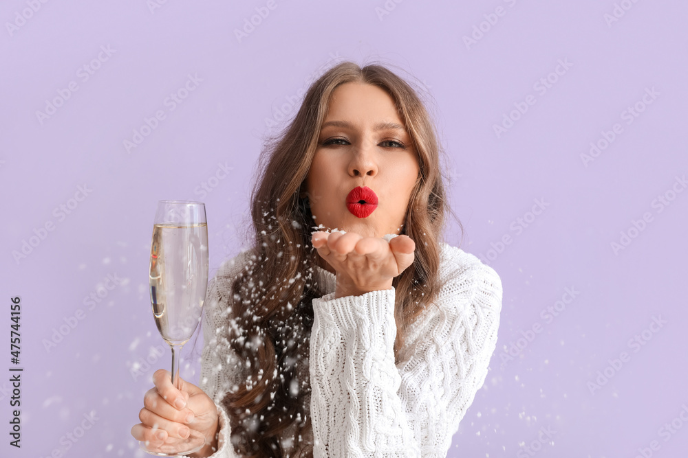 Beautiful young woman with  champagne blowing kiss on color background