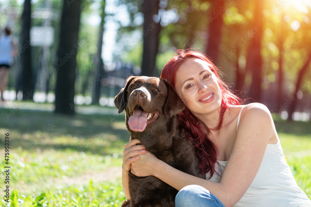 Young attractive woman hugs her dog in the park.