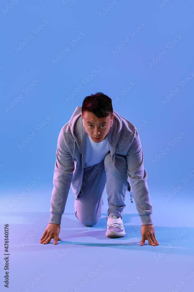 Sporty male runner on color background