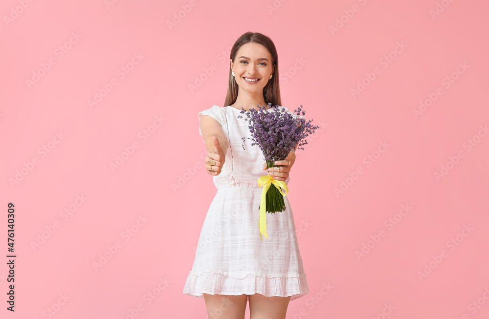 Beautiful young woman with bouquet of lavender showing thumb-up on color background