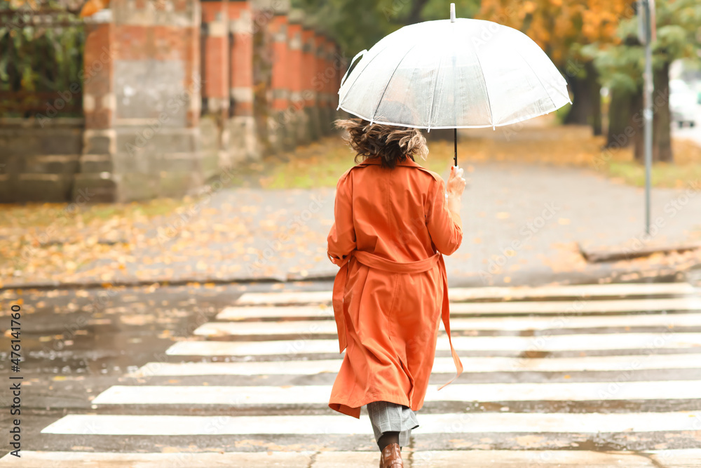 时髦女人带着雨伞和手提包在城市过马路