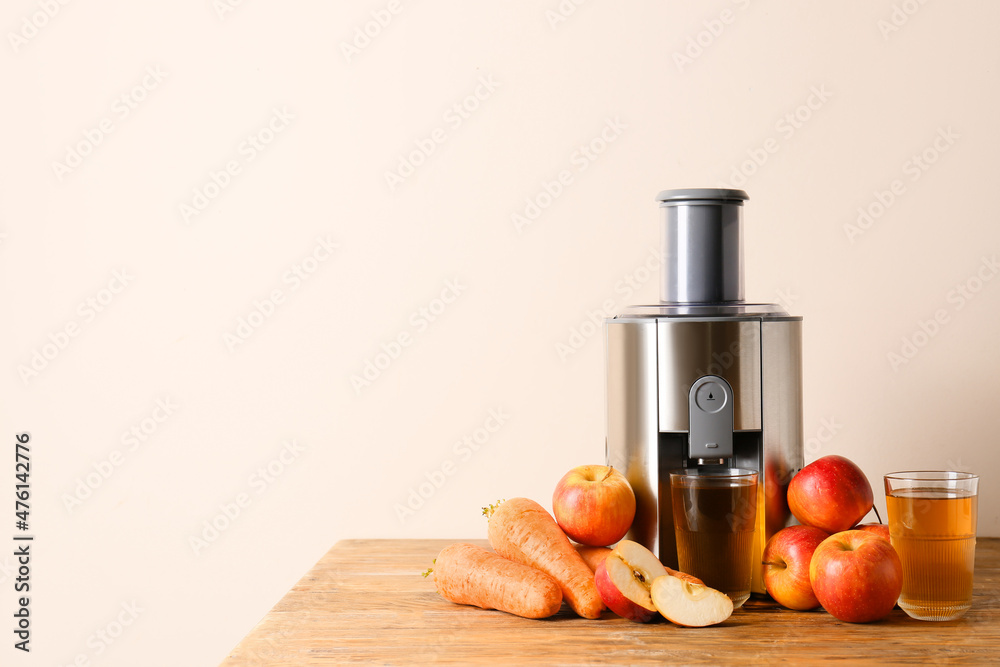 Modern juicer with fresh fruits on table