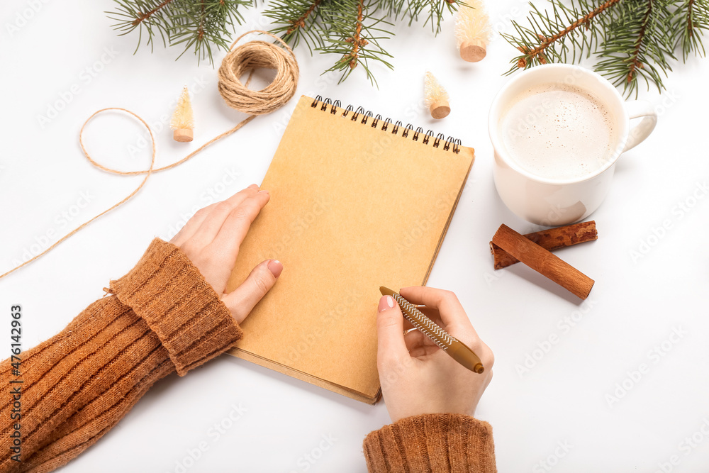 Female hands with blank notebook, pen, cup of cacao and fir branches on white background