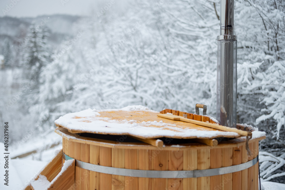 山上雪地露台上的木制热缸。外面有热水浴缸的寒假概念