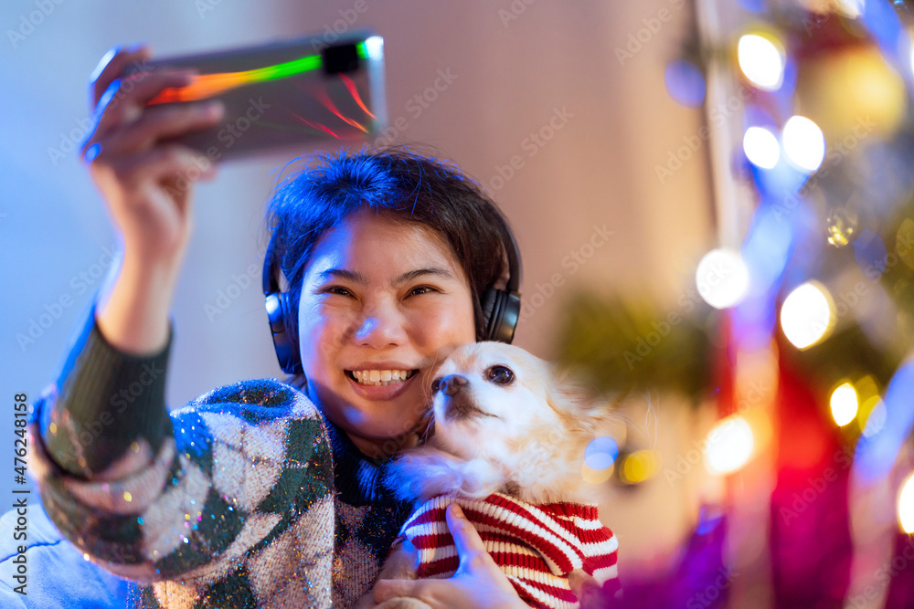 年轻的亚洲成年女性用智能手机与患有sm的小狗自拍