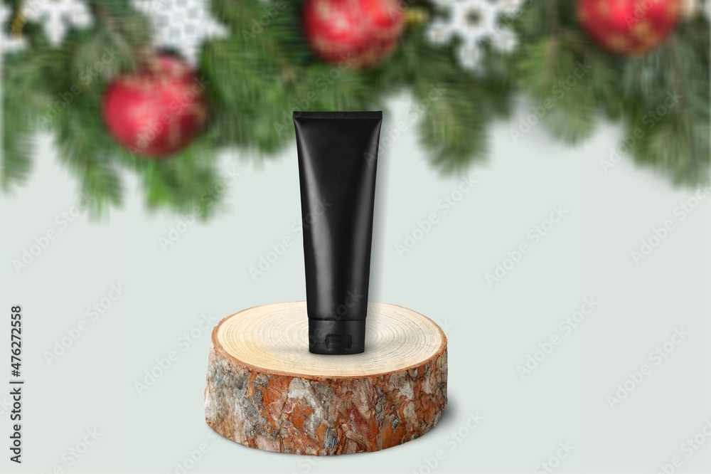 Facial Skincare product tube decorates with Christmas bauble. Cosmetics for festive decoration conce