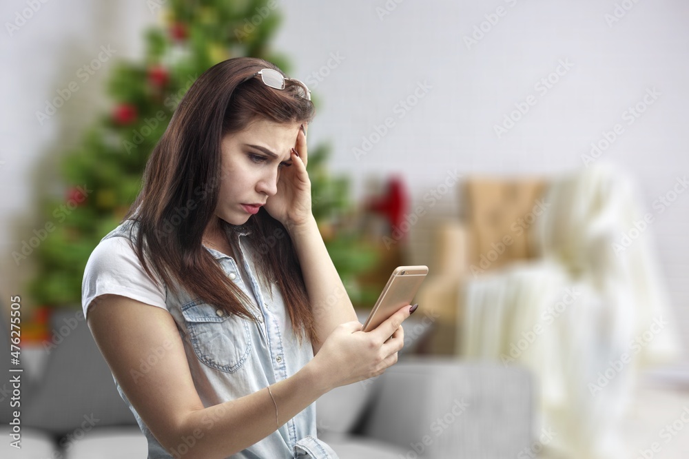 Photo of positive girl typing letter on smartphone sit comfort couch in house indoors with x-mas chr