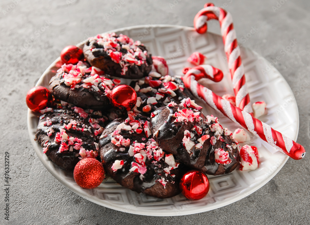 Plate with tasty candy cane cookies on grey background