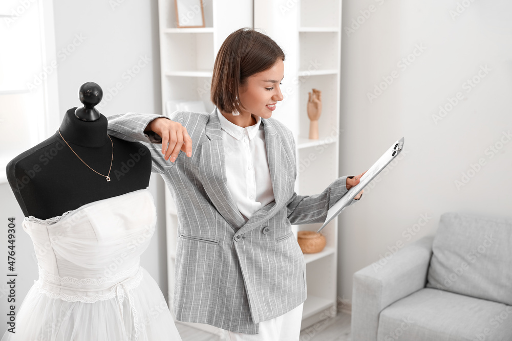 Female wedding planner with beautiful dress and Save the Date Announcement in office