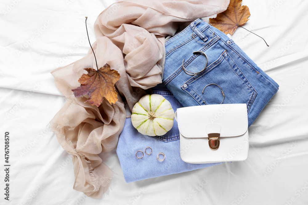 Pumpkin, stylish jeans and female accessories on fabric background