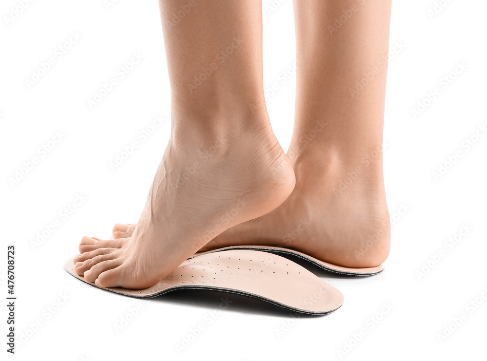 Female feet and orthopedic insoles on white background