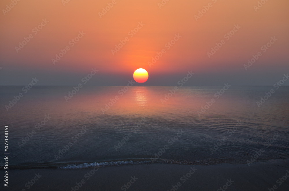 热带沙滩，有平滑的波浪和日落的天空背景。