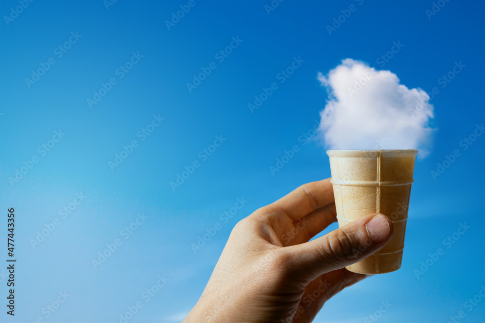 cloud ice cream. hand with waffle cup against blue sky. imagination concept