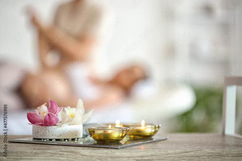 Burning candles with flowers on table in spa salon