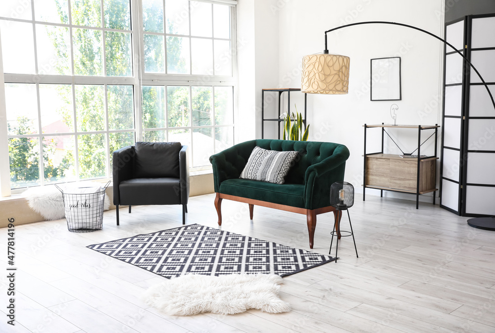 Interior of light living room with green sofa, armchair and lamps