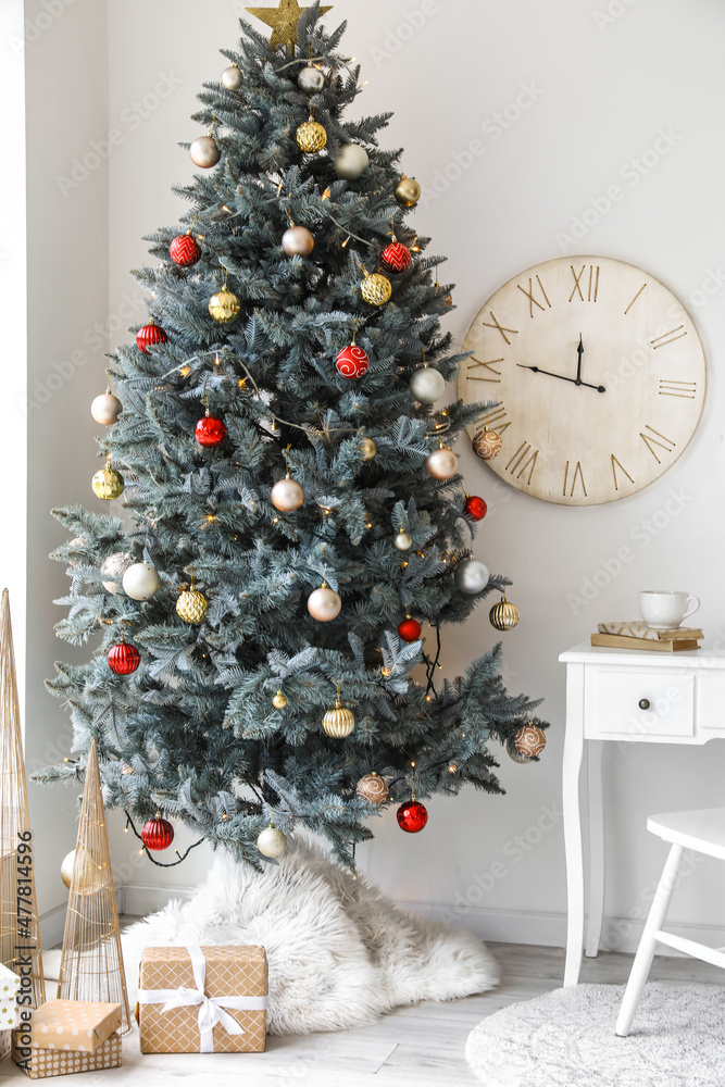 Stylish interior with Christmas tree and clock on light wall