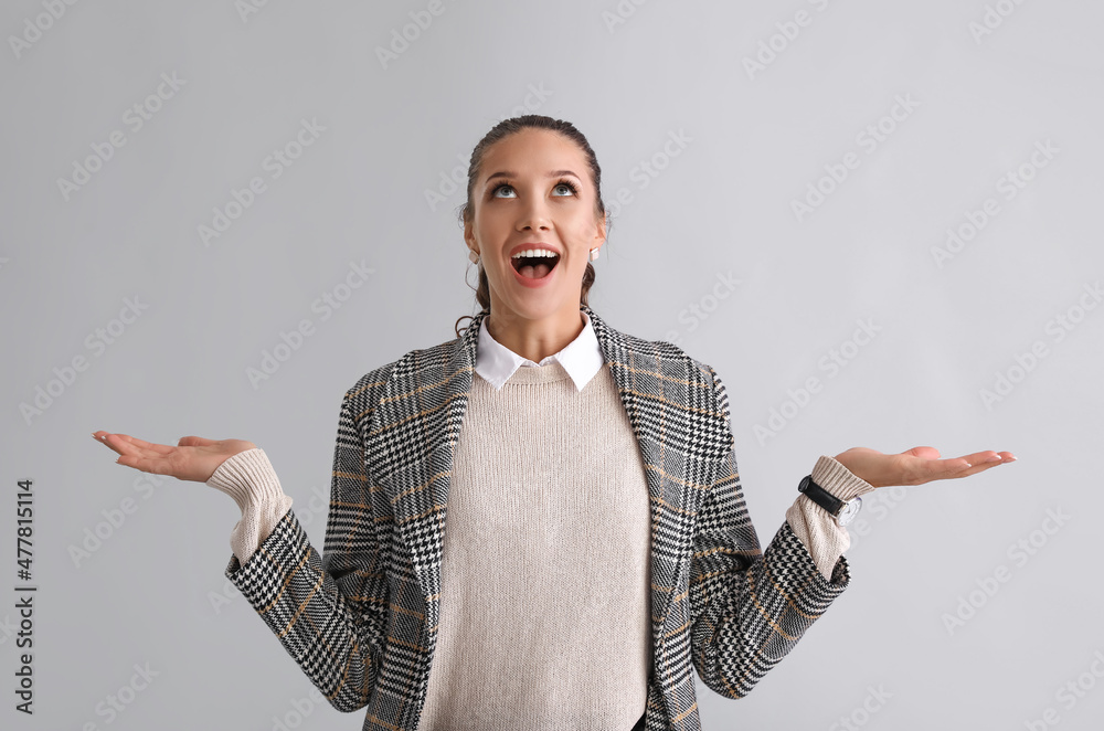 Emotional woman looking up on grey background