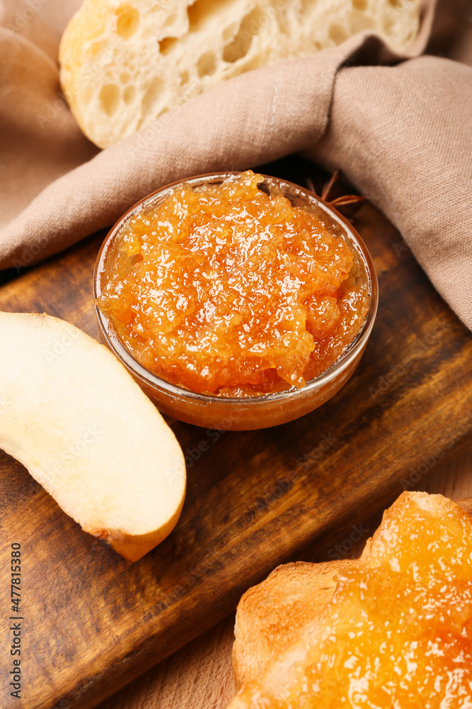 Bowl of tasty pear jam and bread on table, closeup