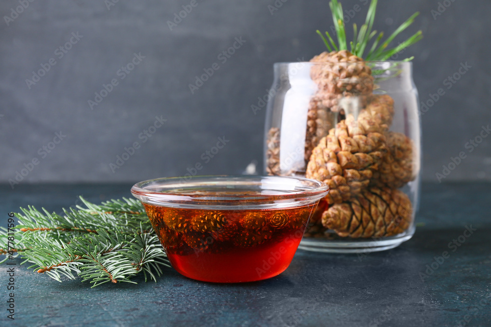 Bowl of tasty pine cone jam and fir tree branch on dark background, closeup