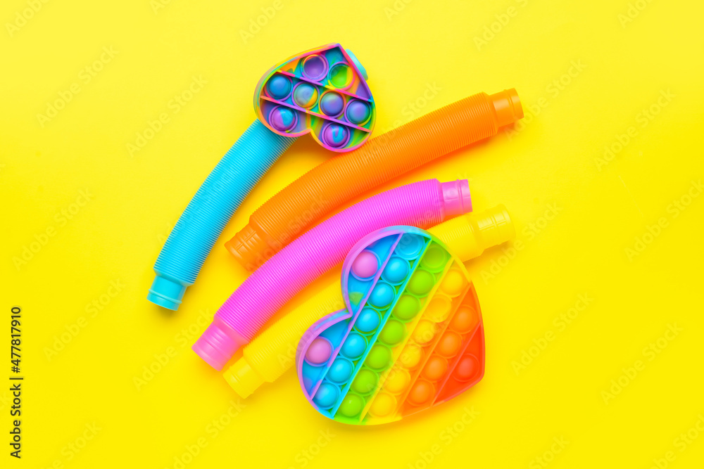 Colorful Pop Tubes and Pop it fidget toys on yellow background