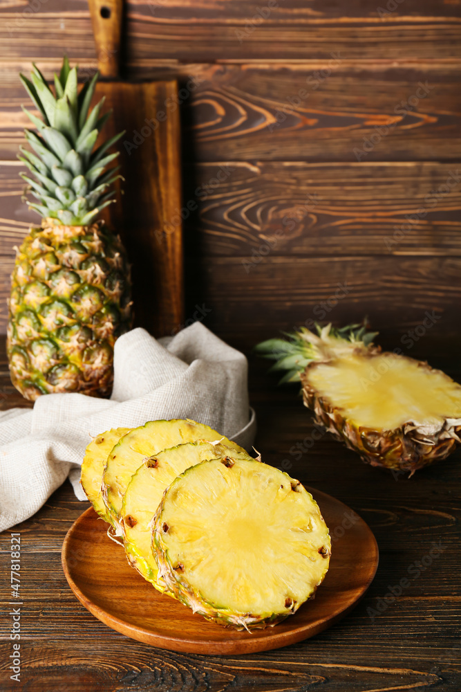 Plate with pieces of ripe juicy pineapple on wooden background