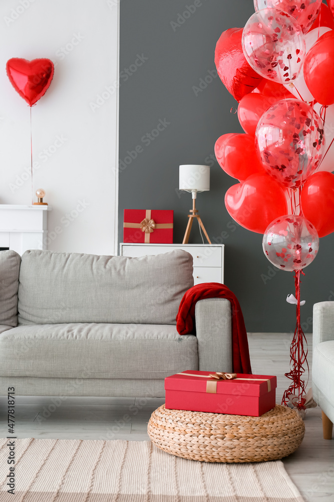 Gift box near sofa in living room decorated for Valentines day