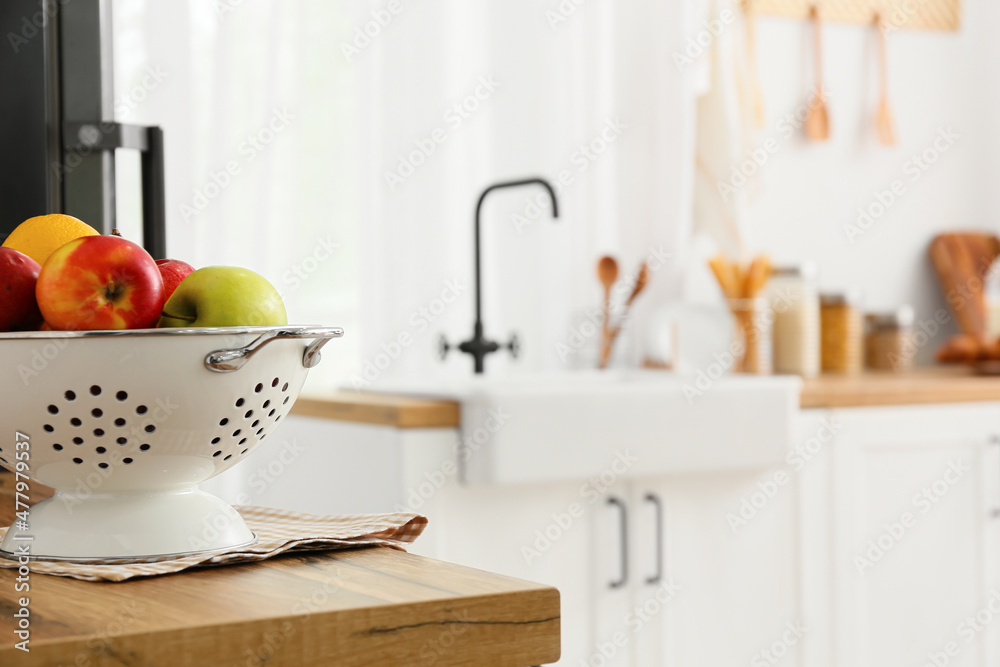 Colander with fruits on wooden table top in kitchen