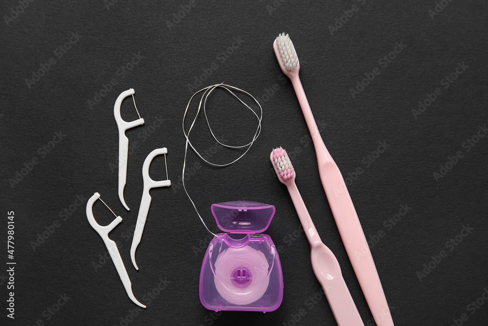 Dental floss with toothpicks and brushes on black background