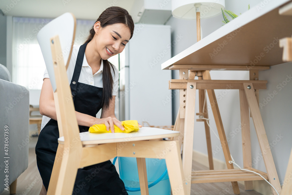 亚洲清洁服务女工在家里的起居室清洁。