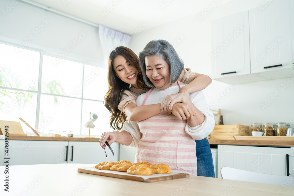 亚洲可爱的家庭，年幼的女儿看着年迈的母亲在厨房做饭