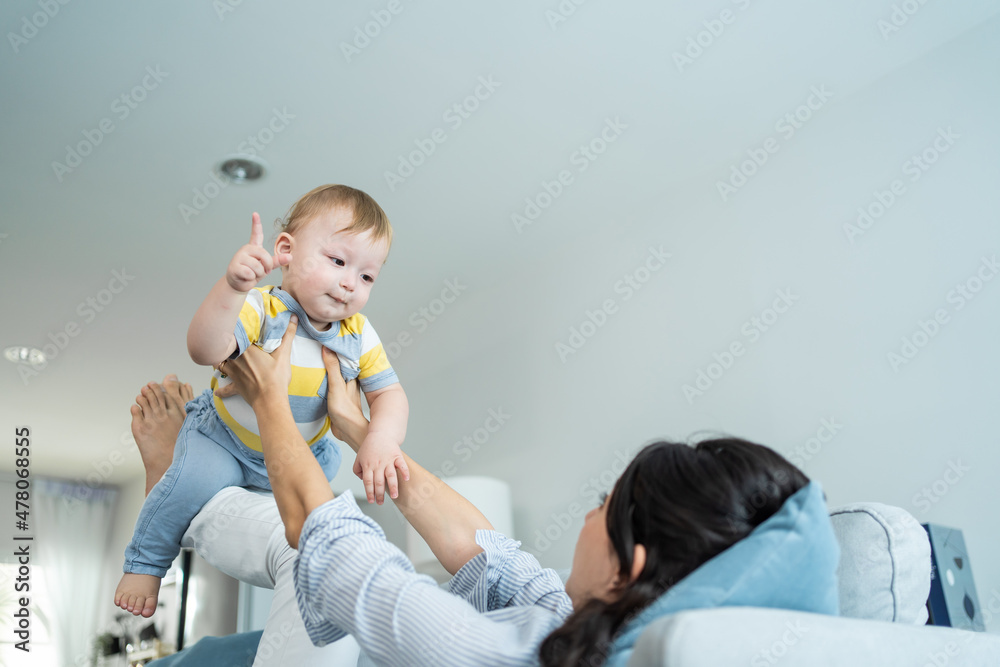 爱高加索的妈妈在客厅的沙发上和男婴玩耍。