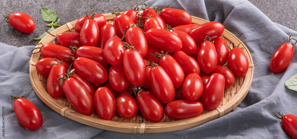 Fresh cherry tomatoes in a basket with basil.