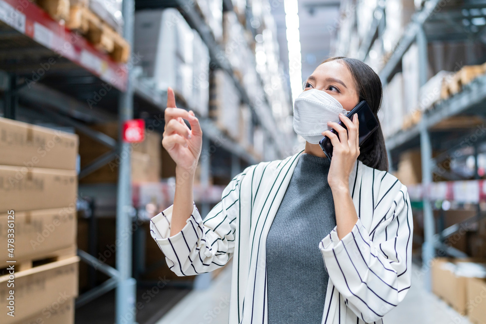 亚洲女企业主戴口罩使用平板电脑检查库存产品库存量的肖像