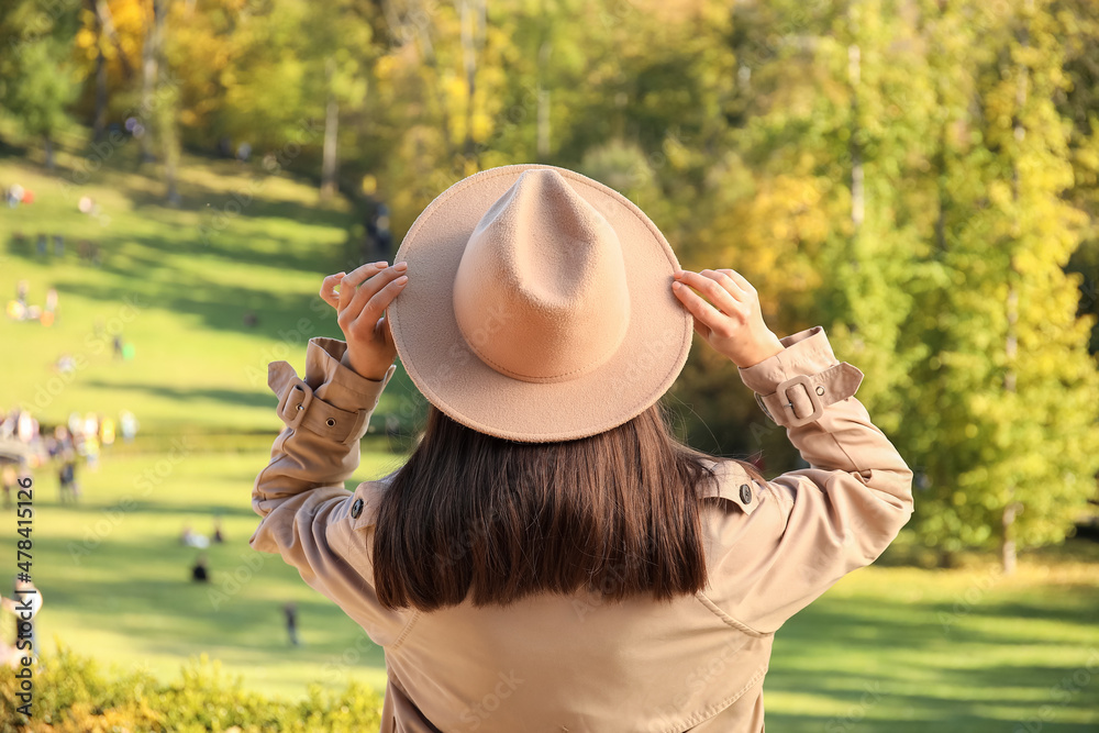 Beautiful brunette woman wearing felt hat on sunny autumn day in park