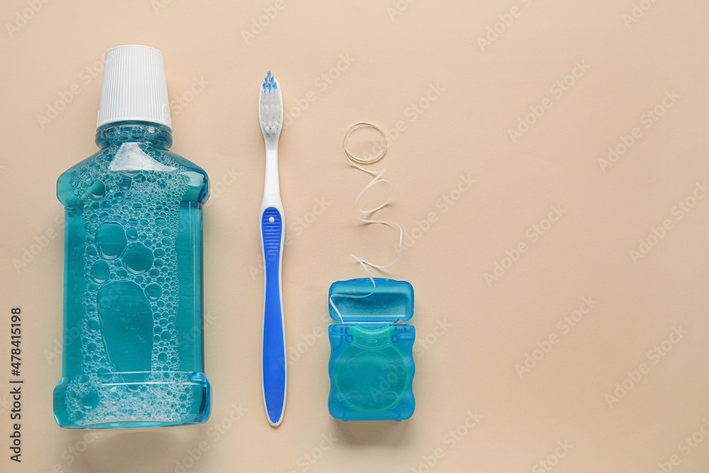 Dental floss, tooth brush and rinse on beige background