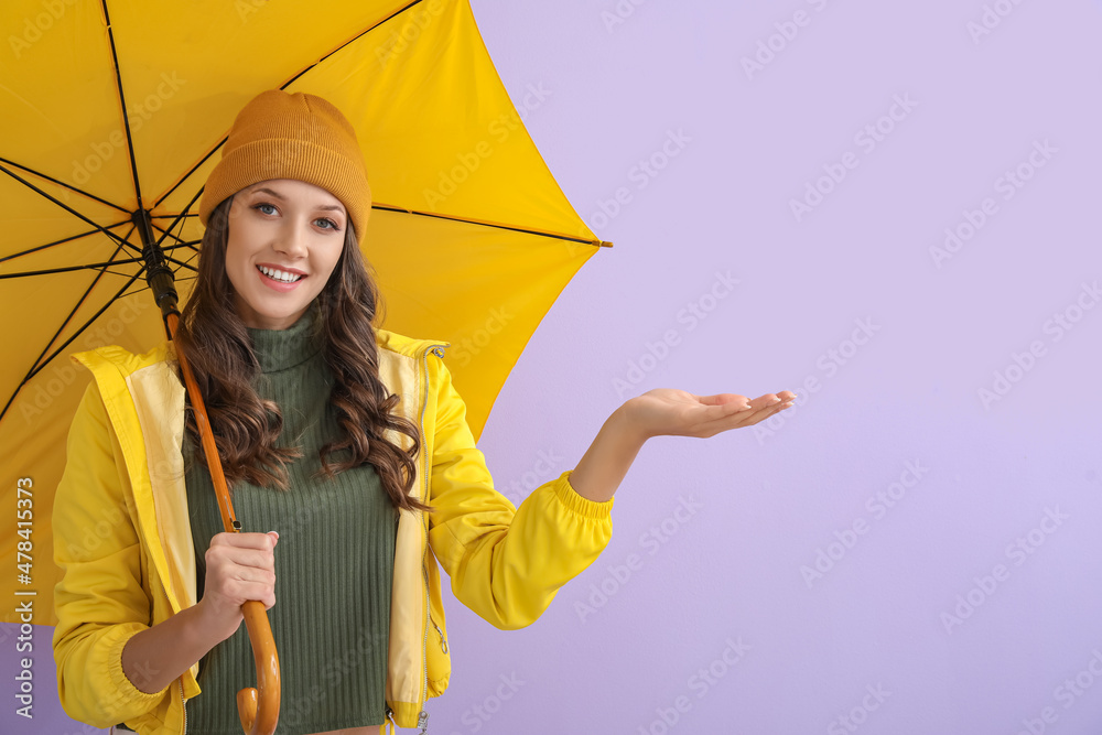 微笑的女人穿着雨衣，在彩色背景上打开雨伞