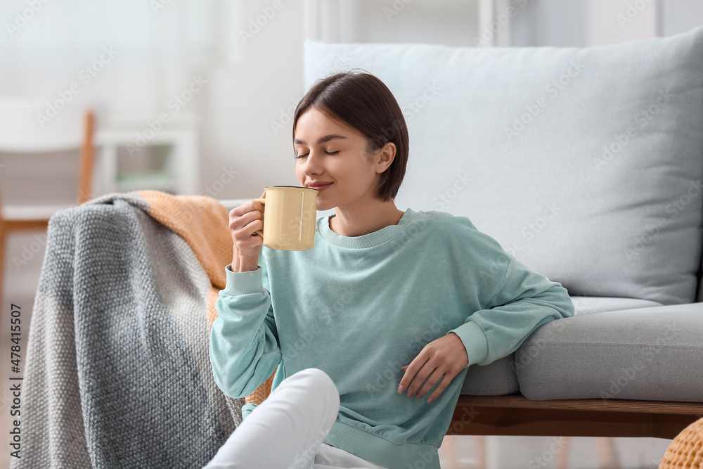 美丽的年轻女人在家里喝着美味的茶