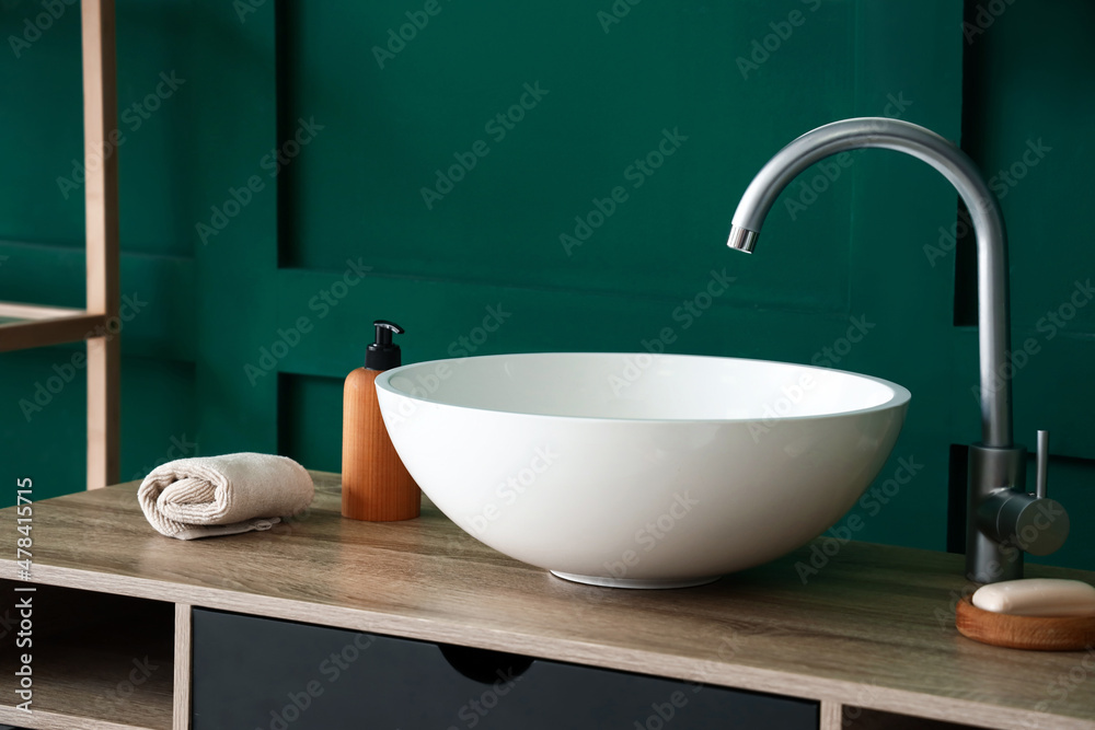 Table with sink and bath supplies near green wall