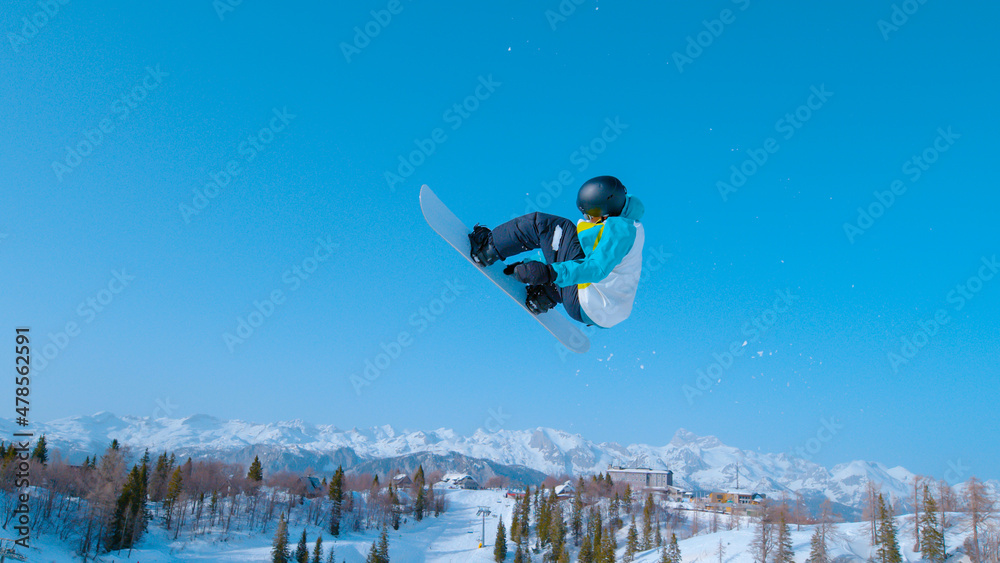 单板滑雪运动员升空，表演旋转抓握技巧。