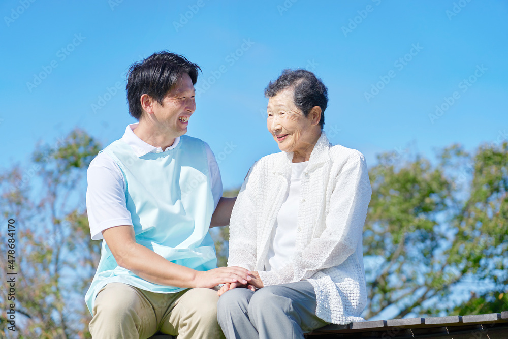 介護士と高齢者　屋外